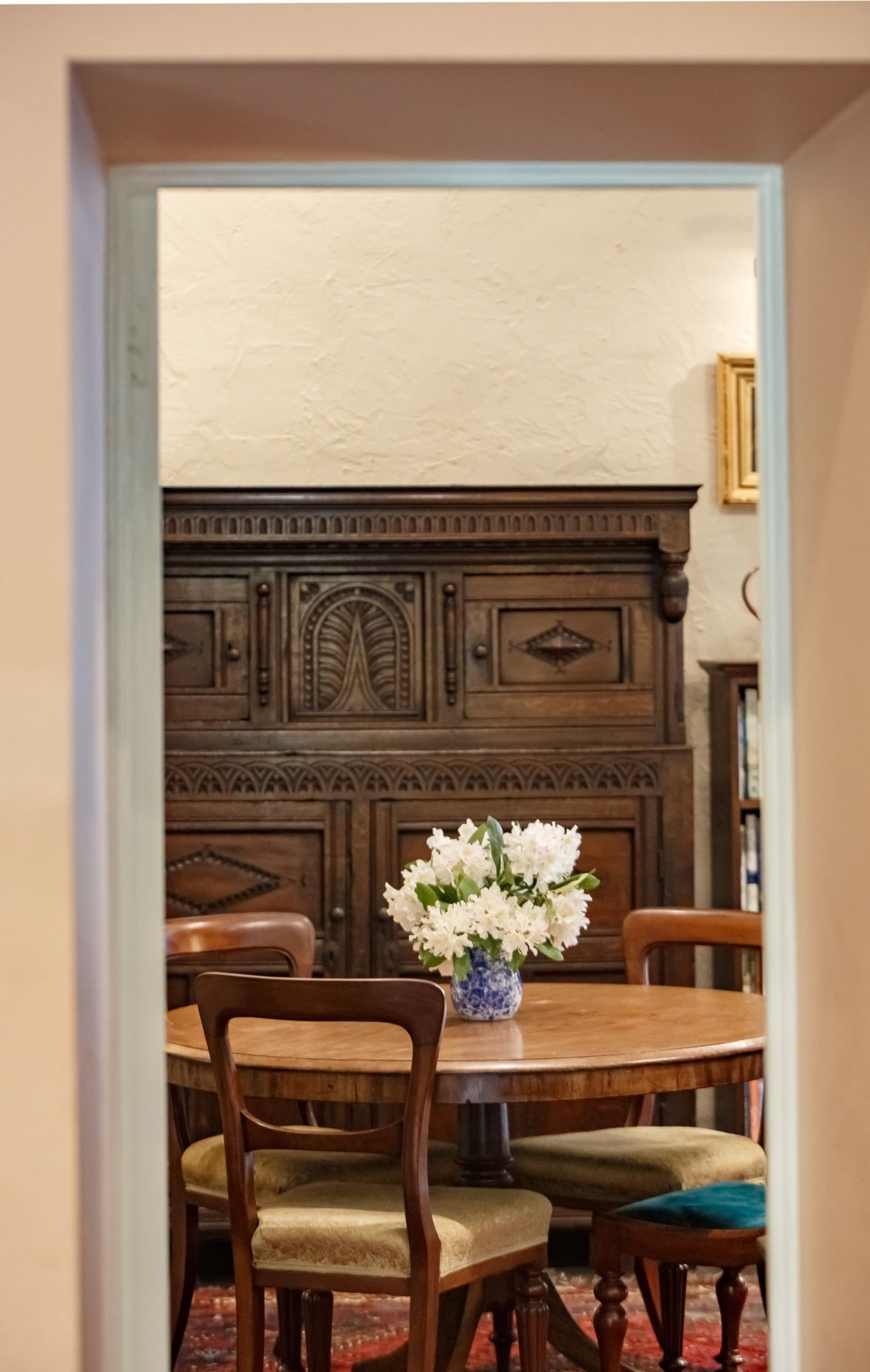 View through a doorway to an antique carved dresser and dining table